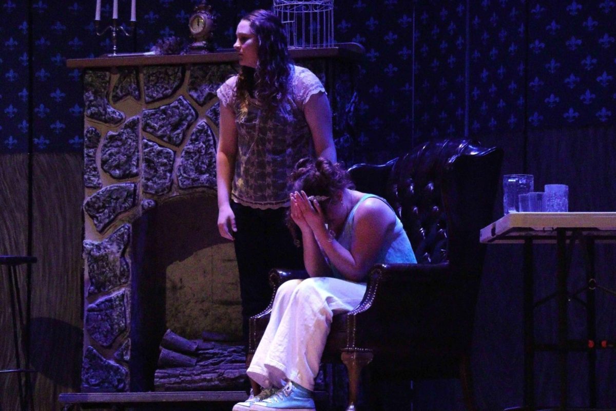 Junior Claire Keller sobs with her head in her hands, while Freshman Lacey Calhoun stands next to her.