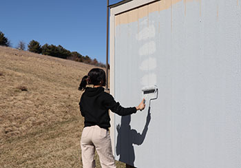 Sophomore Elsa Gebremicheal uses a painting roller on the Habitat shed. "I like this but I don't like my stained shirt," said Gebremicheal.