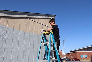 Sophomore Josiah Nafziger paints the top of the shed wall. " I've done this plenty of times It's like I have a rhythm," said Nafziger.