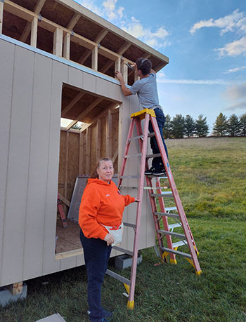 Ms Cloud holds the ladder for Josiah Nafziger then says "just making sure he doesn't fall. That would be a problem."