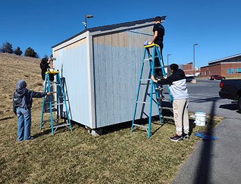 Omar Hernandez and Multezem Siraj helps hold up ladder. Siraj says, " I'm just glad I'm not up there."