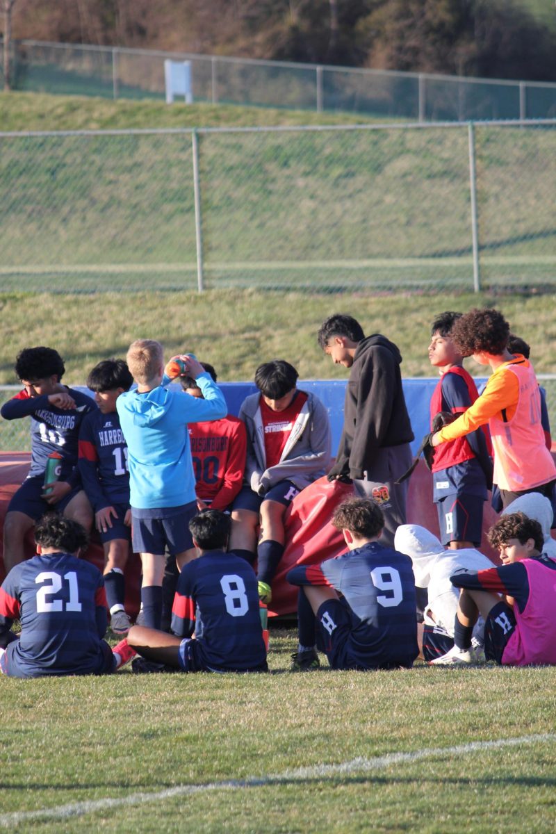 Its halftime the team is listening to the coaches focused on the game. They all work hard and are tired, but haven't given up yet. It's a tied game at this point and they are going to put their all in this last half.