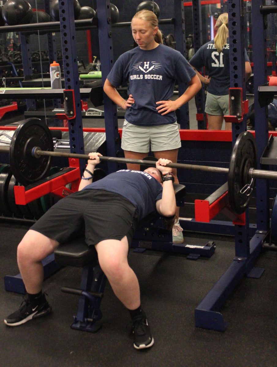 Ava Colley is benching with the help of Katie Grace. As Colley works hard, Grace watches ready to help if she starts struggling. 