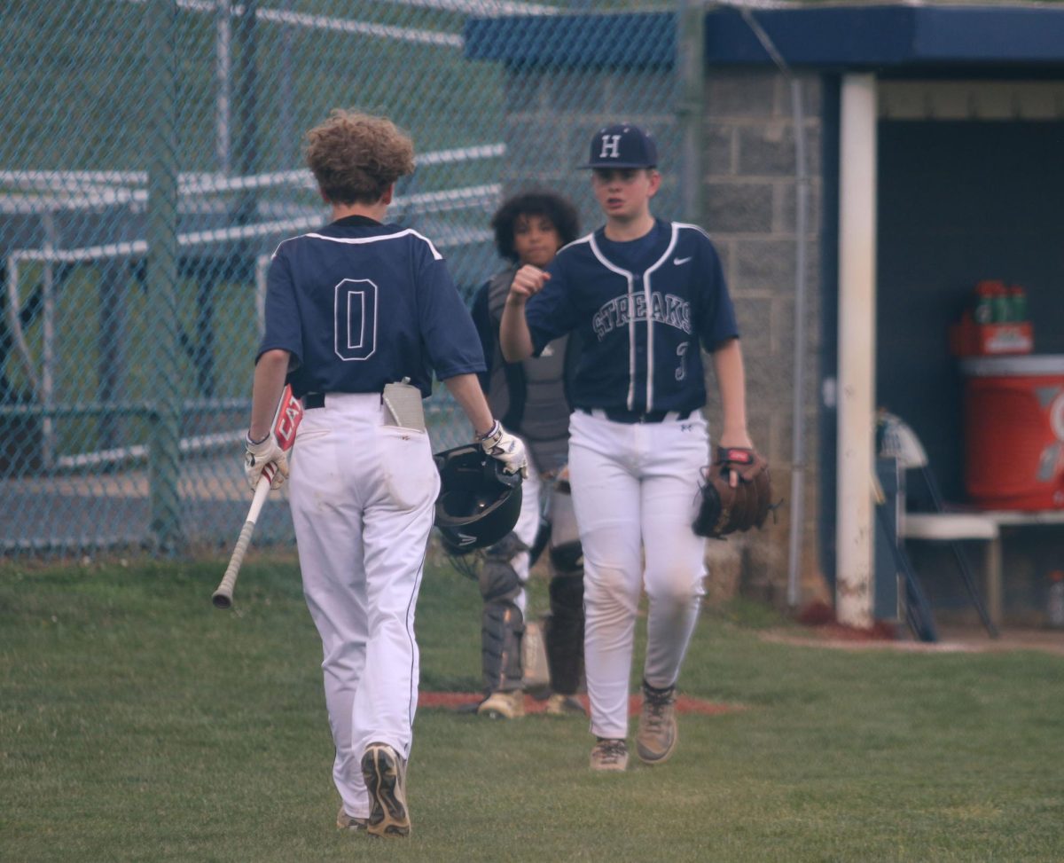 Eighth grader Andrew Noll congratulates teammate Rylan Smith after getting a hit