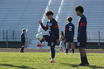 Jeferson Rivera Mazariegos kicking the ball while Alfredo Rivero-Rodriguez is watching.
