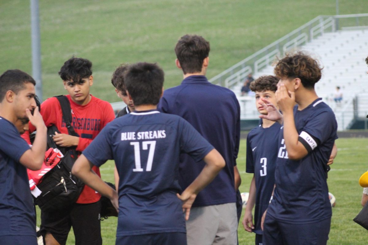 Coach gives feedback to JV boys soccer team. 