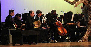 The orchestra plays behind the trees. Seniors Donovan Eanes and Chloe Starling worked together to compose the music. "We started by just playing around," Starling says.