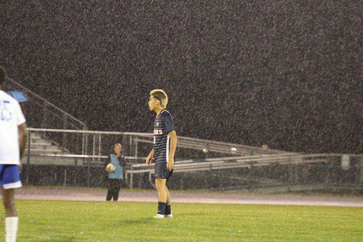 Junior Edison Rattana standing on the field while the rain is pouring.