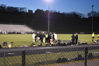 HHS soccer coach pull the team in for a pre-game meeting.