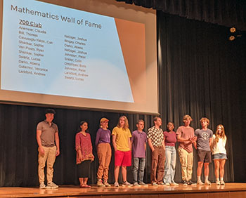 The members of the "700 club" (people who got 700+ on the math section of the SAT) stand on stage to be honored.