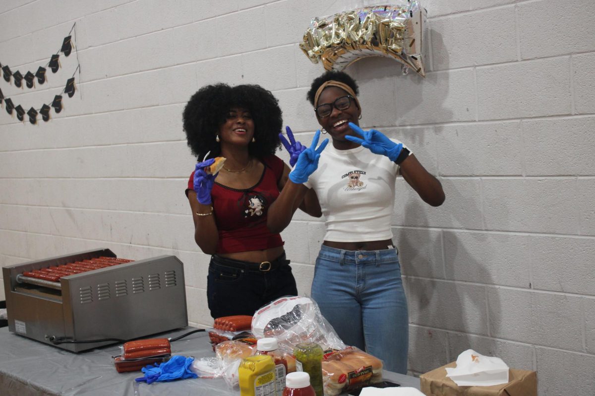 Linda and her friend cook some hot dogs for seniors.