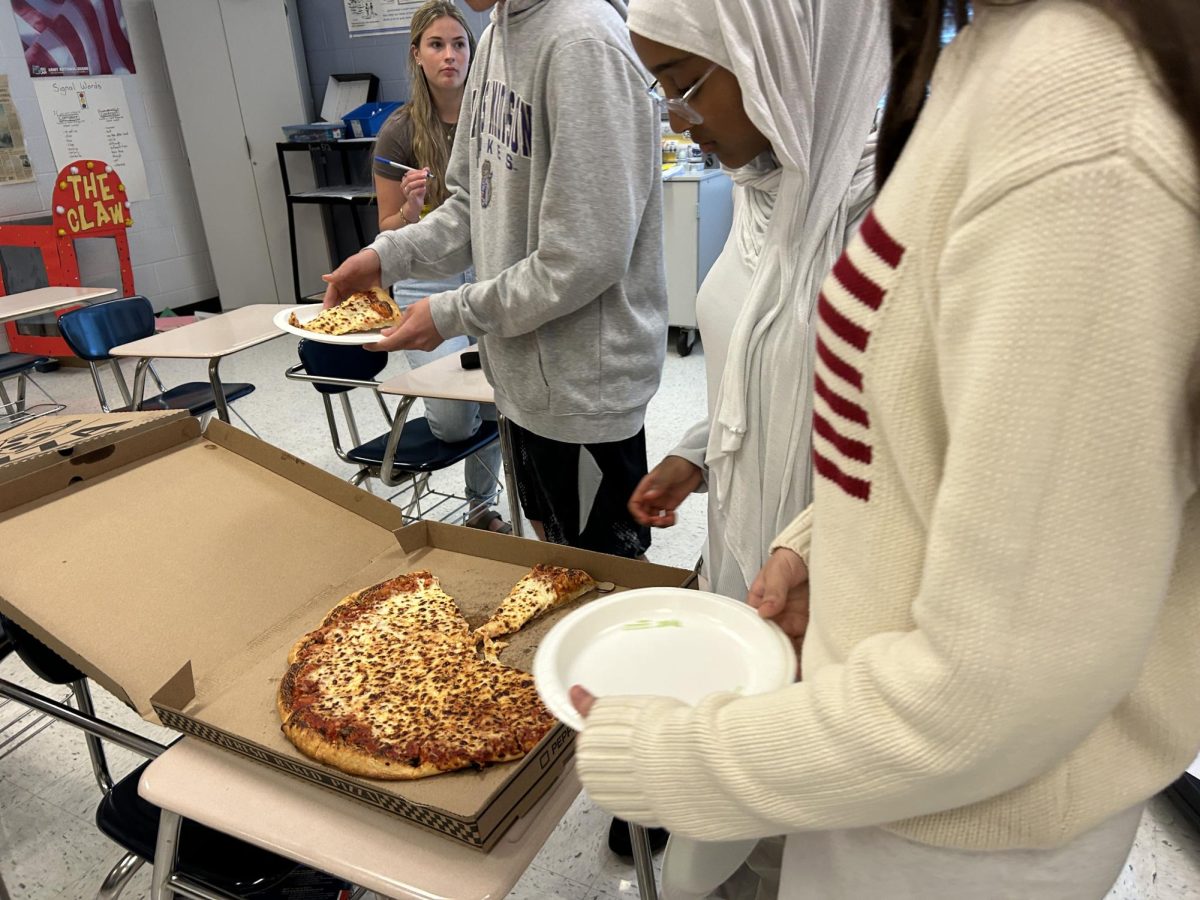 Freshmen Leonita Rexha taking a slice of pizza.