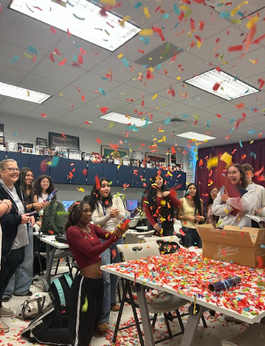 Estephany Ortega blows confetti celebrating the yearbooks coming in.