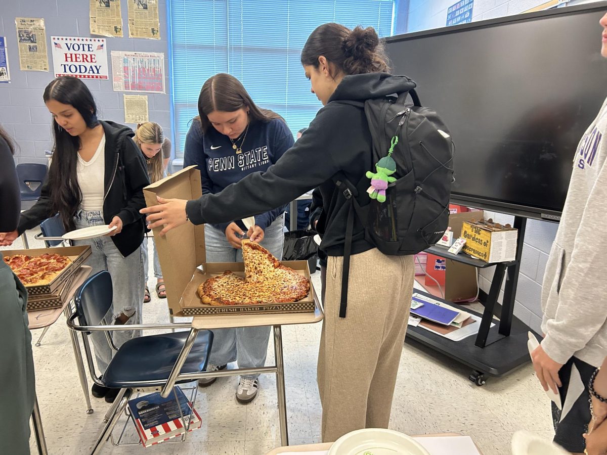 Junior Delan Hamund holding the pizza box for student.