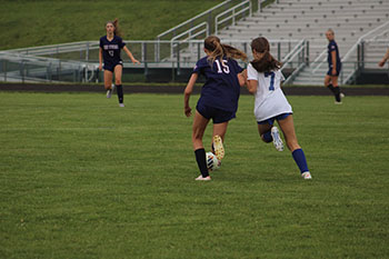 These two girls are fighting to get the ball to score a point for their team.