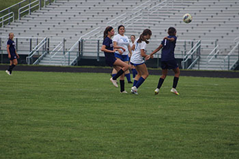 As the ball is in the air, the girls are right on its tail to steal it.