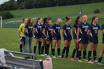 The girls are standing for the pledge of allegiance.