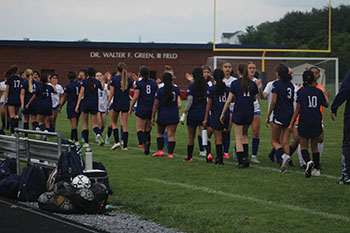 The girls are standing for the pledge of allegiance.