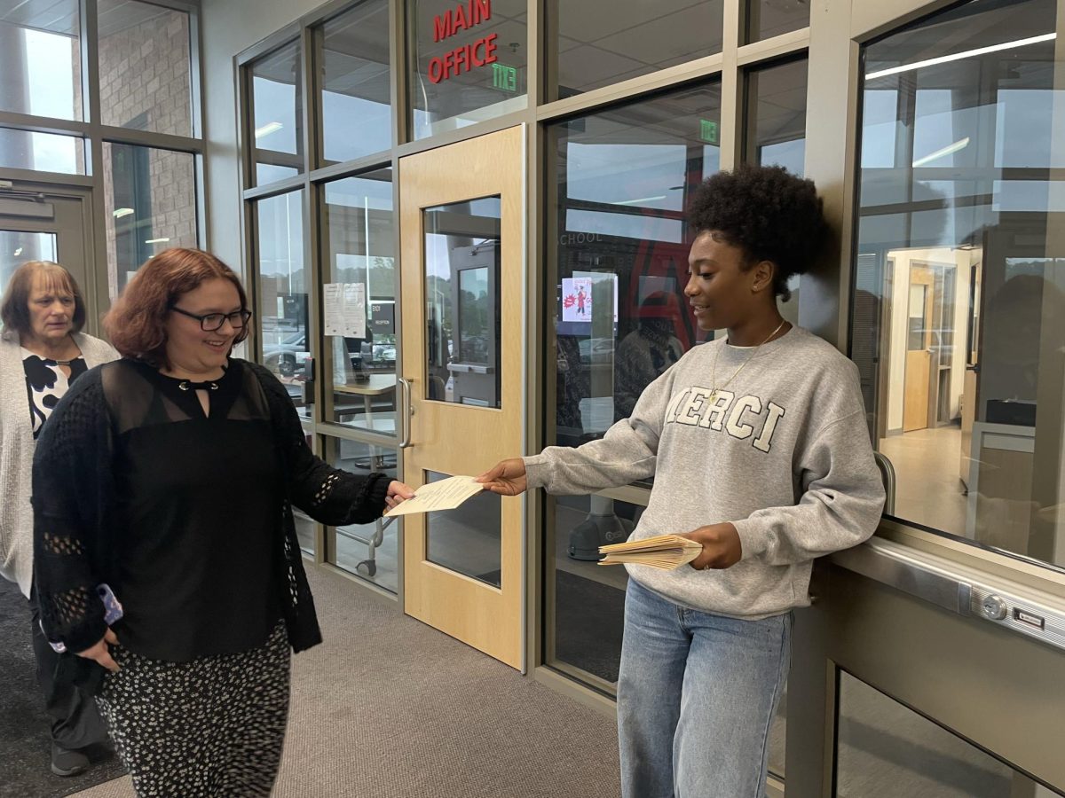 Sophomore Kaylen De Los Santos Medina passes out booklets. 