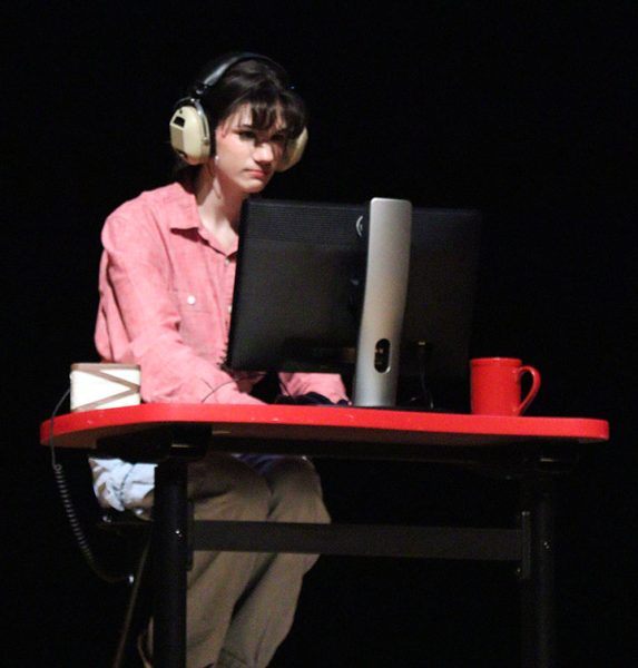 A 911 operator, played by Lila Hostetler, listens to a frantic caller.