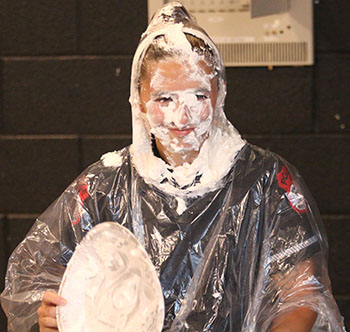 Officer Miller holds the empty pie tray with its contents on her face.