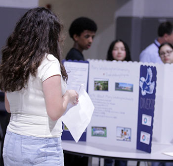 An eighth grader writes notes on a college board. Students who fill their page earn a piece of candy.