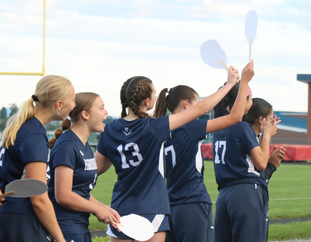 The Varsity girls soccer team waves signs for their seniors.
