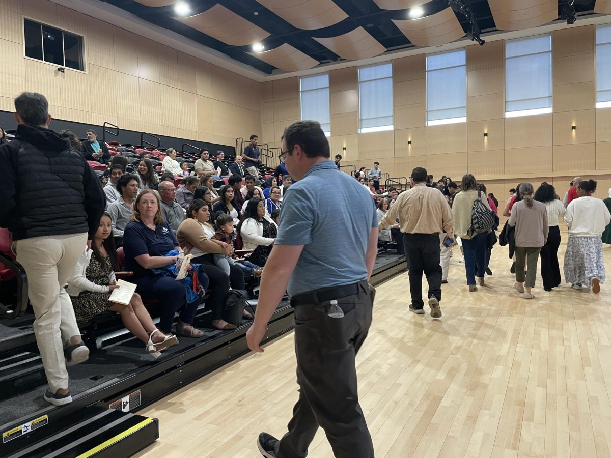 Families and students enter the room to listen to announcements, watch the video, and receive their cords. 
