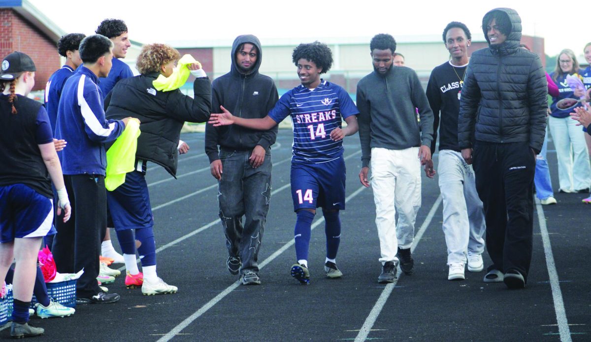 Senior Temesgen Habtemicheal is walked by friends while being honored for senior night.