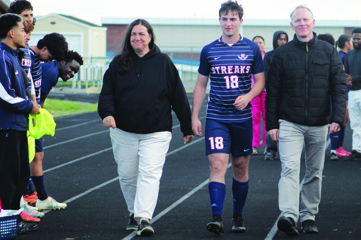Senior Arlo Von Rotz is walked out by his parents during senior night.