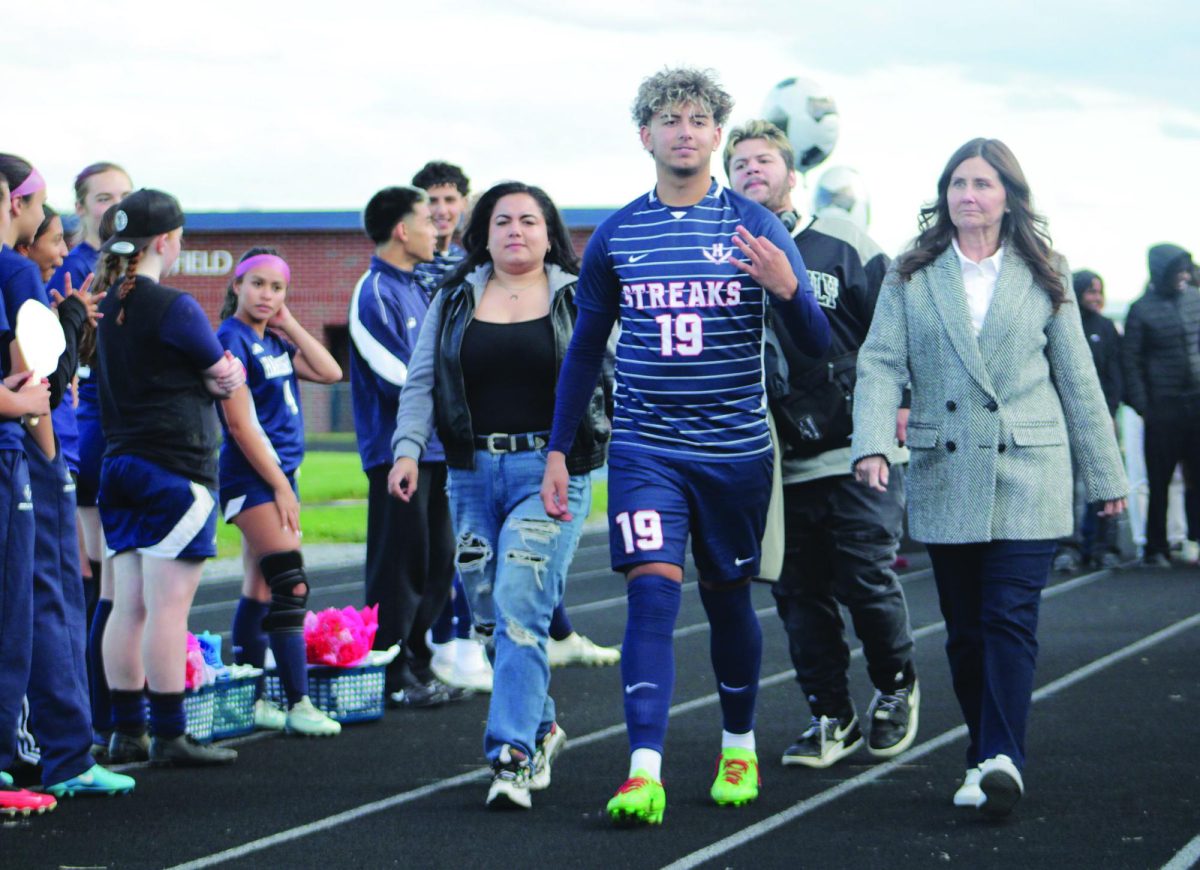 Senior Rayyan Garout is walked out by family members to be honored on senior night.