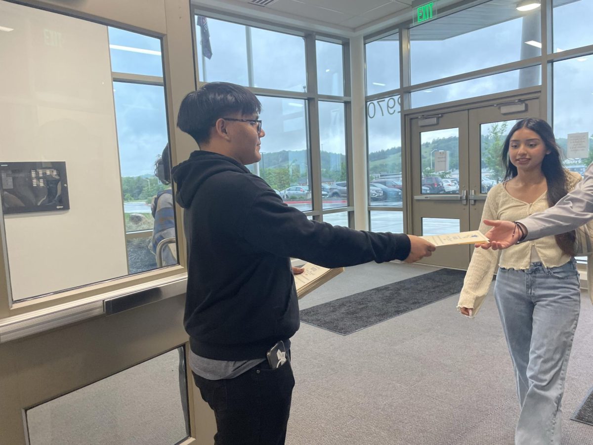 Sophomore Teodoro Gallardo hands out the booklets. 