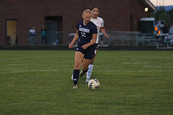 HHS girls varsity soccer player kicking the ball to her teammate.