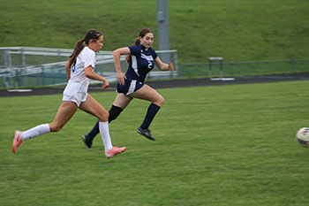 HHS varsity soccer team player trying to take the ball from broadway opponent.