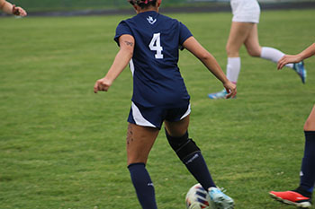 Soccer girl varsity player #4 takes the ball from the opponent.