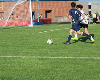 Varsity player #11 running towards the soccer ball.