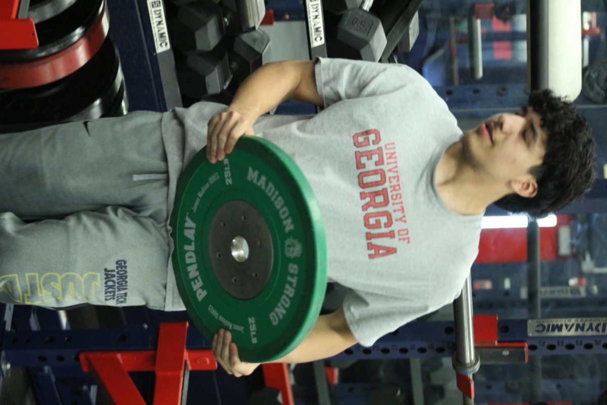 Fernando Rodriguez is putting weight on the bar before helping his classmate with benching.