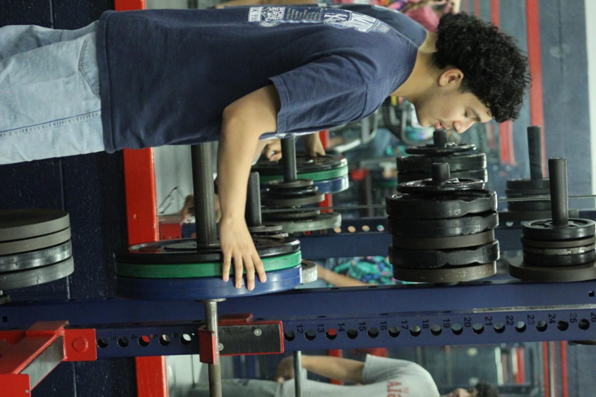 Edwin Martinez is putting weight on the bar before helping his classmate, Fernando Rodriguez bench. 