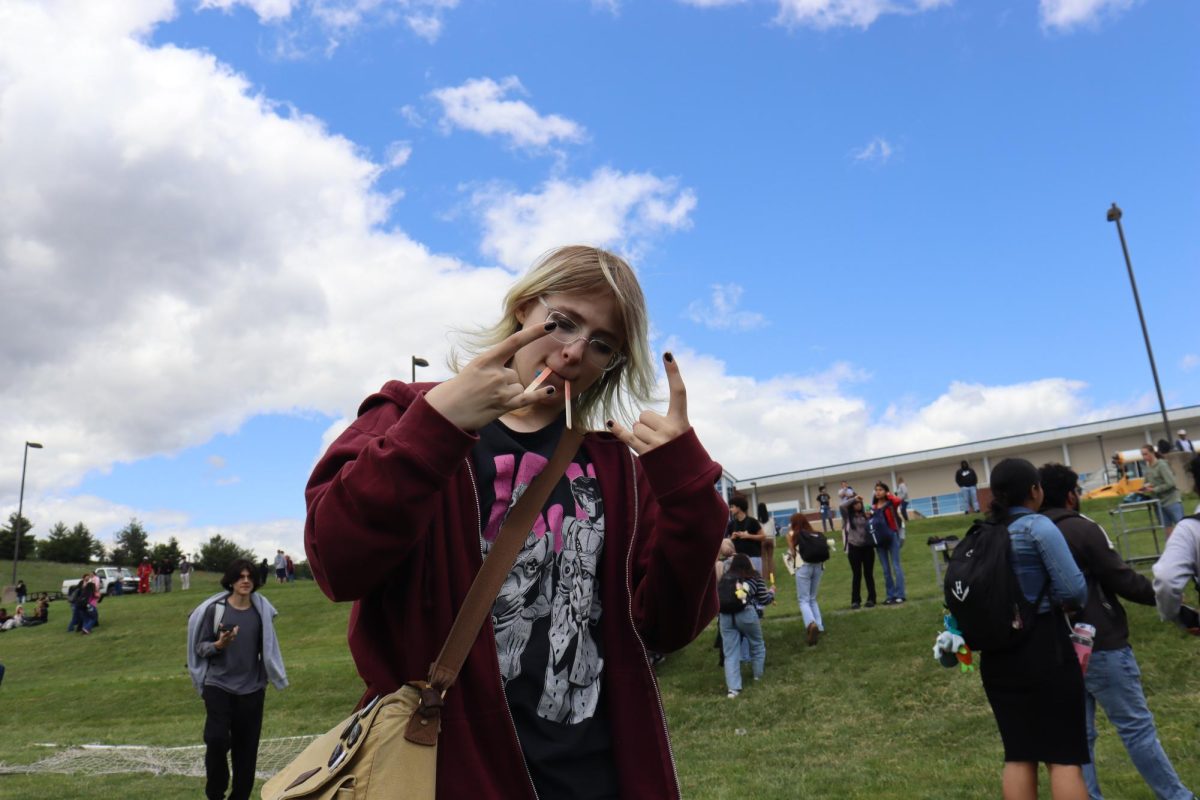 Sophomore Eren Gaines poses with two popsicle sticks in their mouth, imitating a walrus.