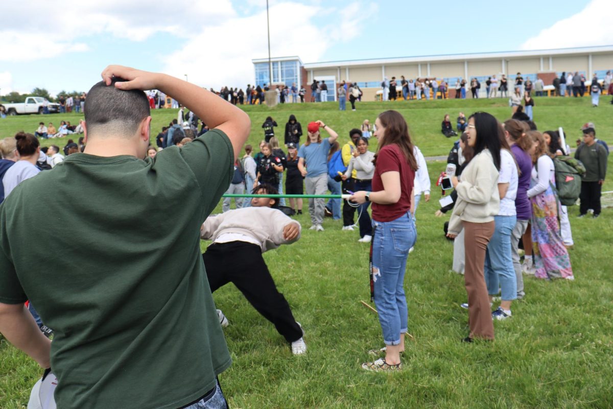 A student ducks down low to get under the limbo bar.