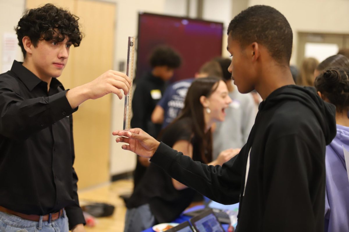 Senior Can Cavusoglu Yalcin tests another student's reflexes at the STEMinar. He is the STEM Academy president, and played a part part in planning the event. "Even though we started out a little rough, we feel like the students had a lot of fun and all the officers did a great job", Cavusoglu Yalcin said.