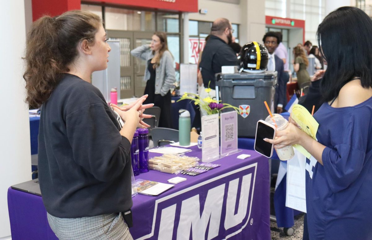 A high school student shows interest in the James Madison University Education table