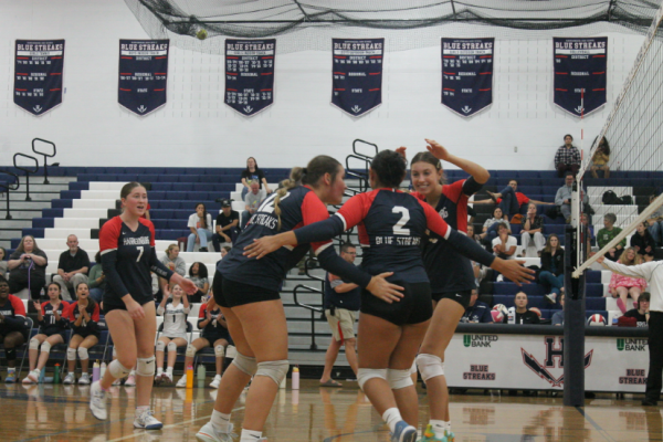 The varsity team celebrates winning a point in a big huddle.