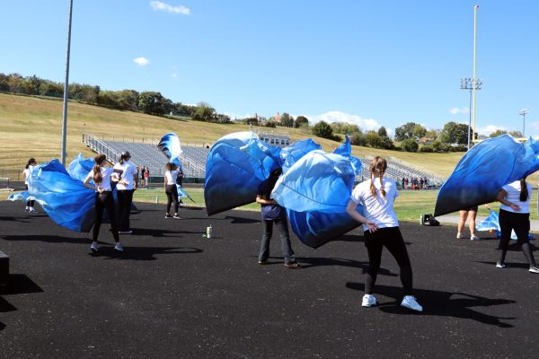 Colorguard members spin swing flags.