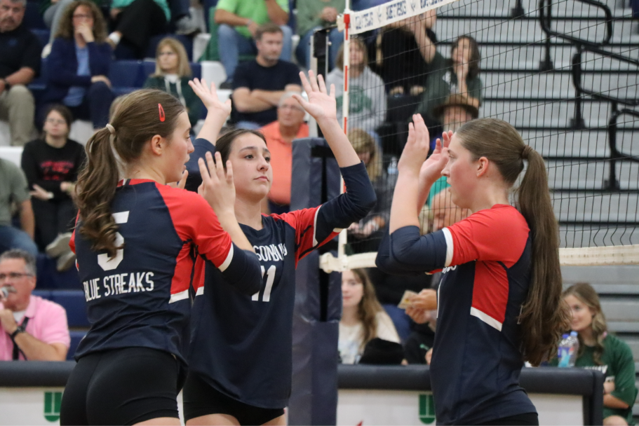 Junior Nora Von Rotz, freshman Brently Riner, and sophomore Delaney Dayton high five each other before the next play.