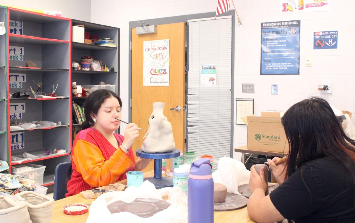 student paints details into the vase