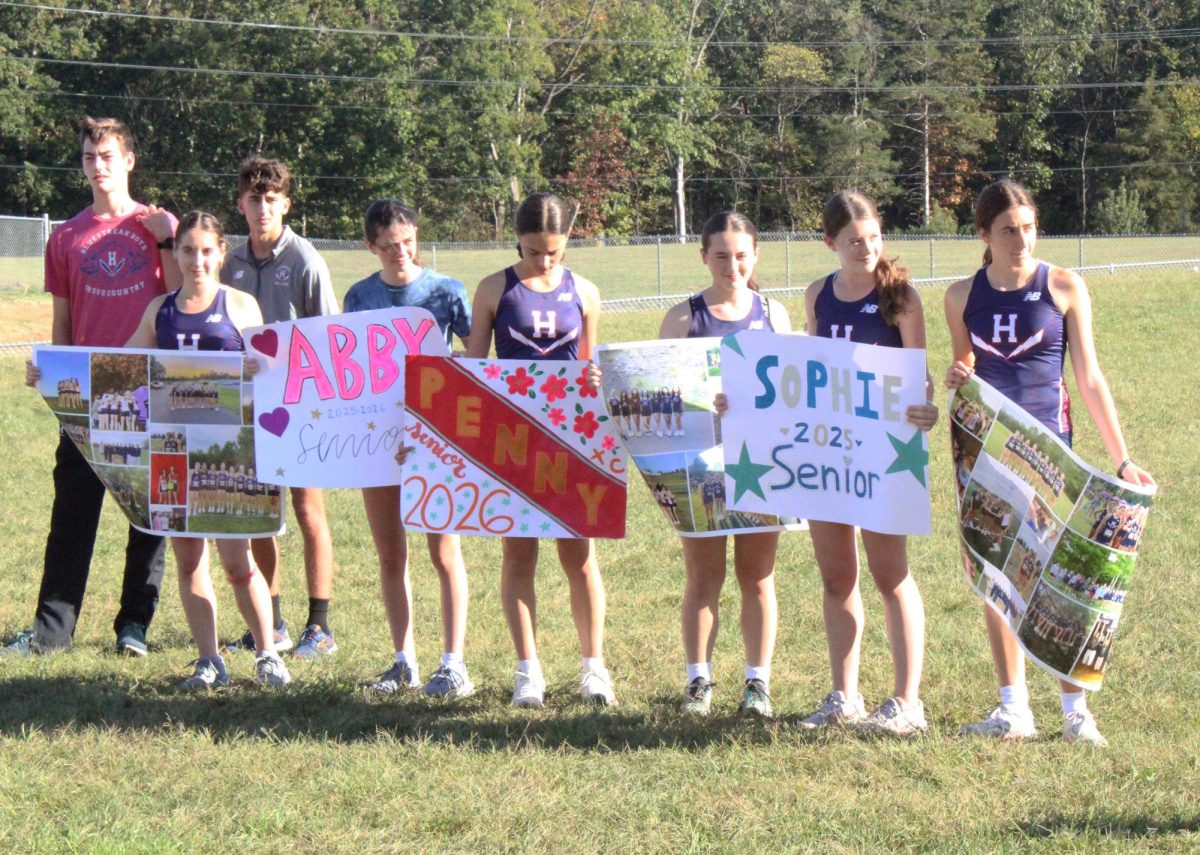 Girls cross country team holds signs for their seniors.